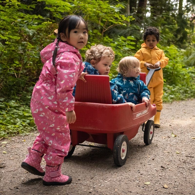 Children playing with a red wagon in a forest setting