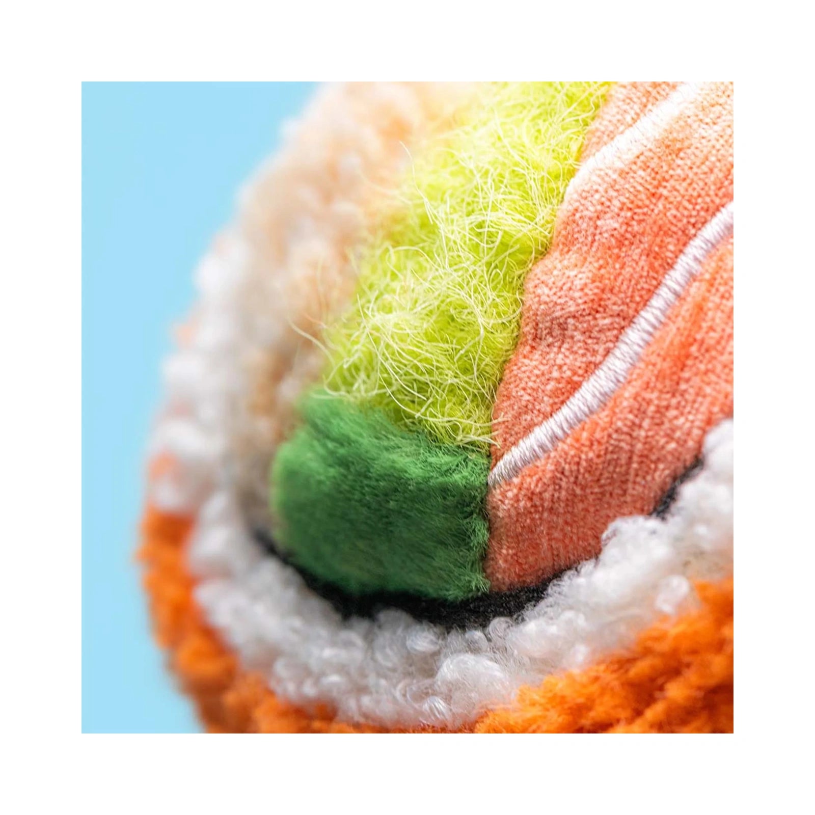 A close up detail of the Jellycat Amuseables Codhi Californian Roll plush toy, showcasing the textured orange, white, green, and yellow fabrics mimicking sushi ingredients.