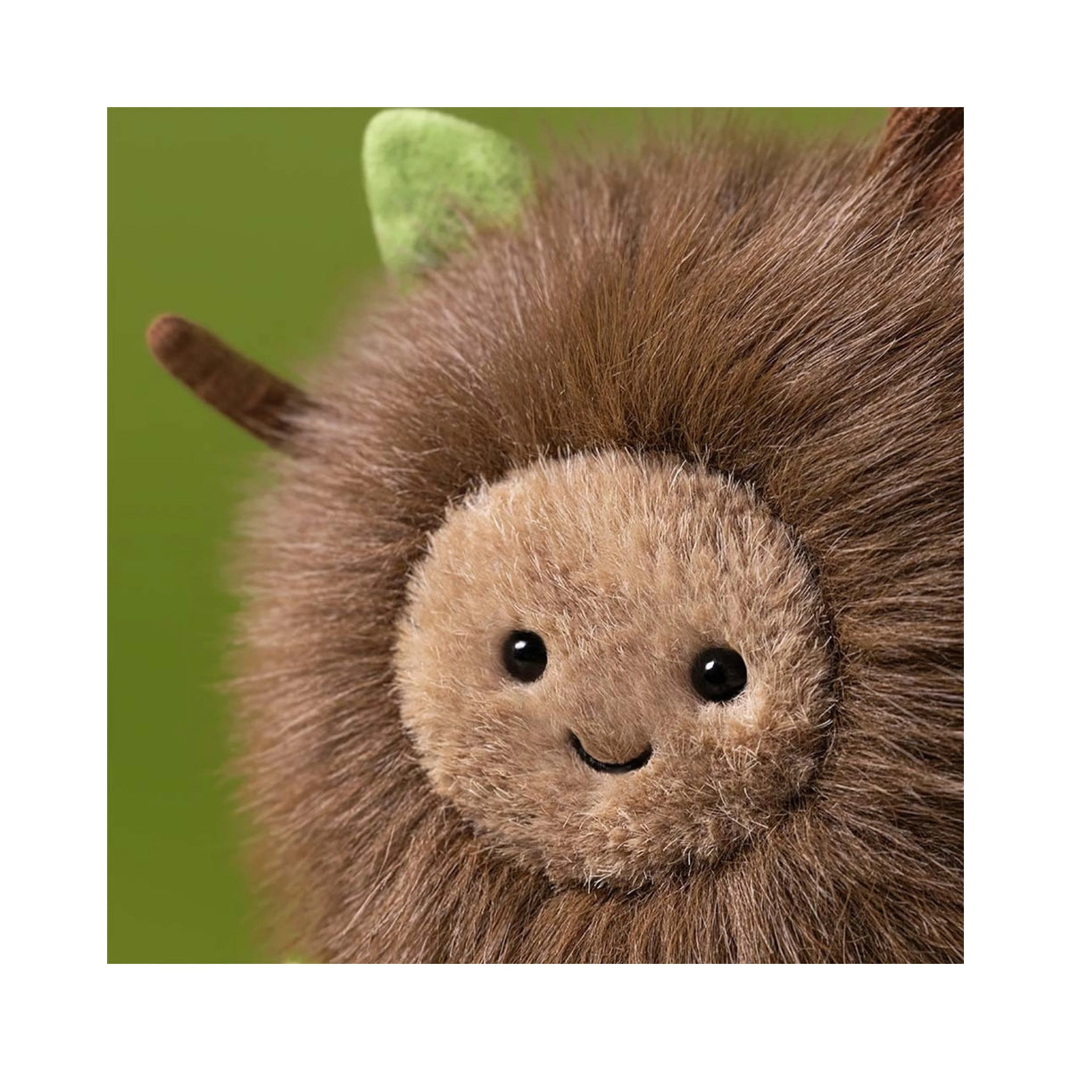 Close up detail of Jellycat Amuseables Mulshi Woodland Floor showing smiling embroidered face and green leaf.
