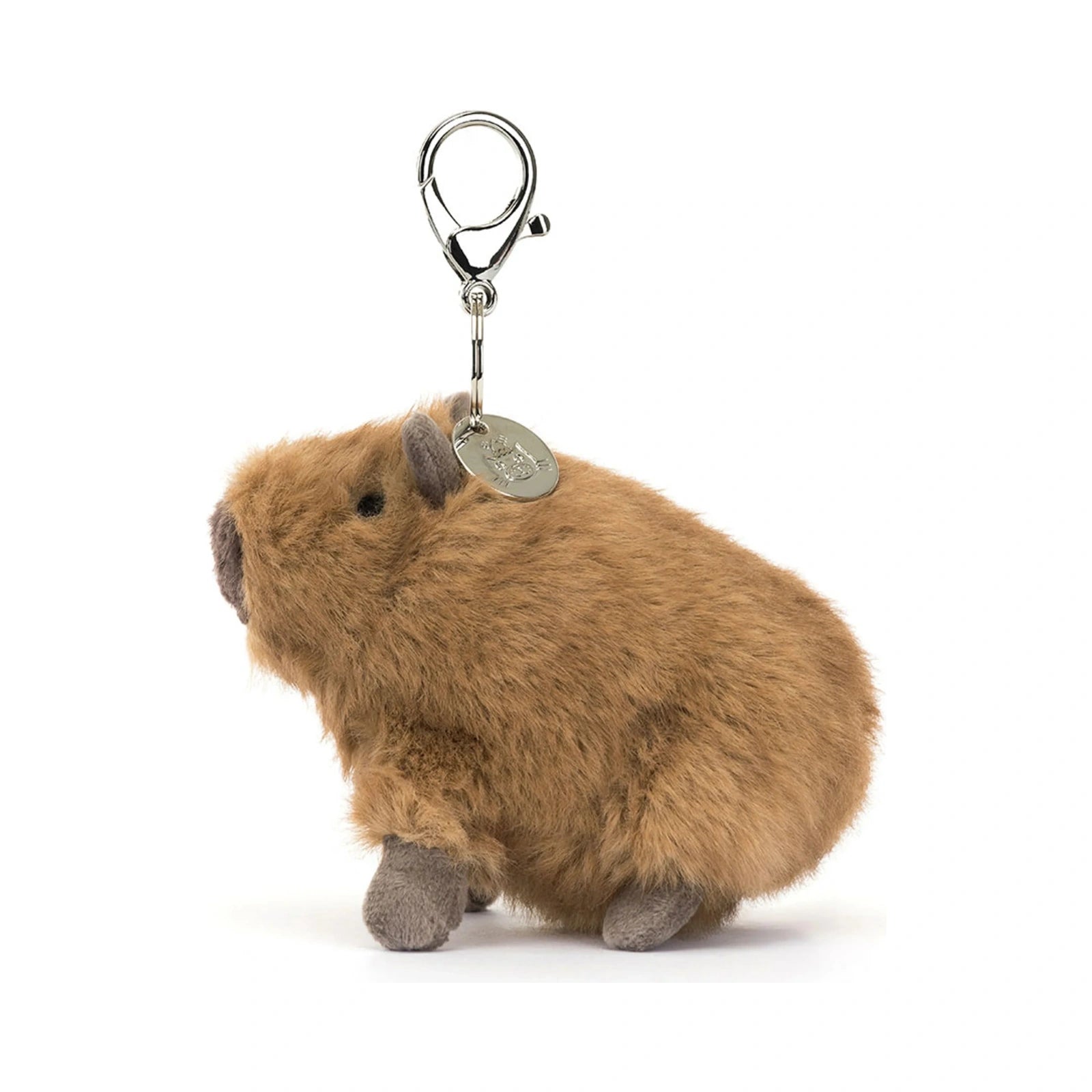 A Jellycat Clyde Capybara Clip On Charm features a small fluffy brown plush capybara with grey ears and feet, attached to a silver metal clasp with a round branded tag.