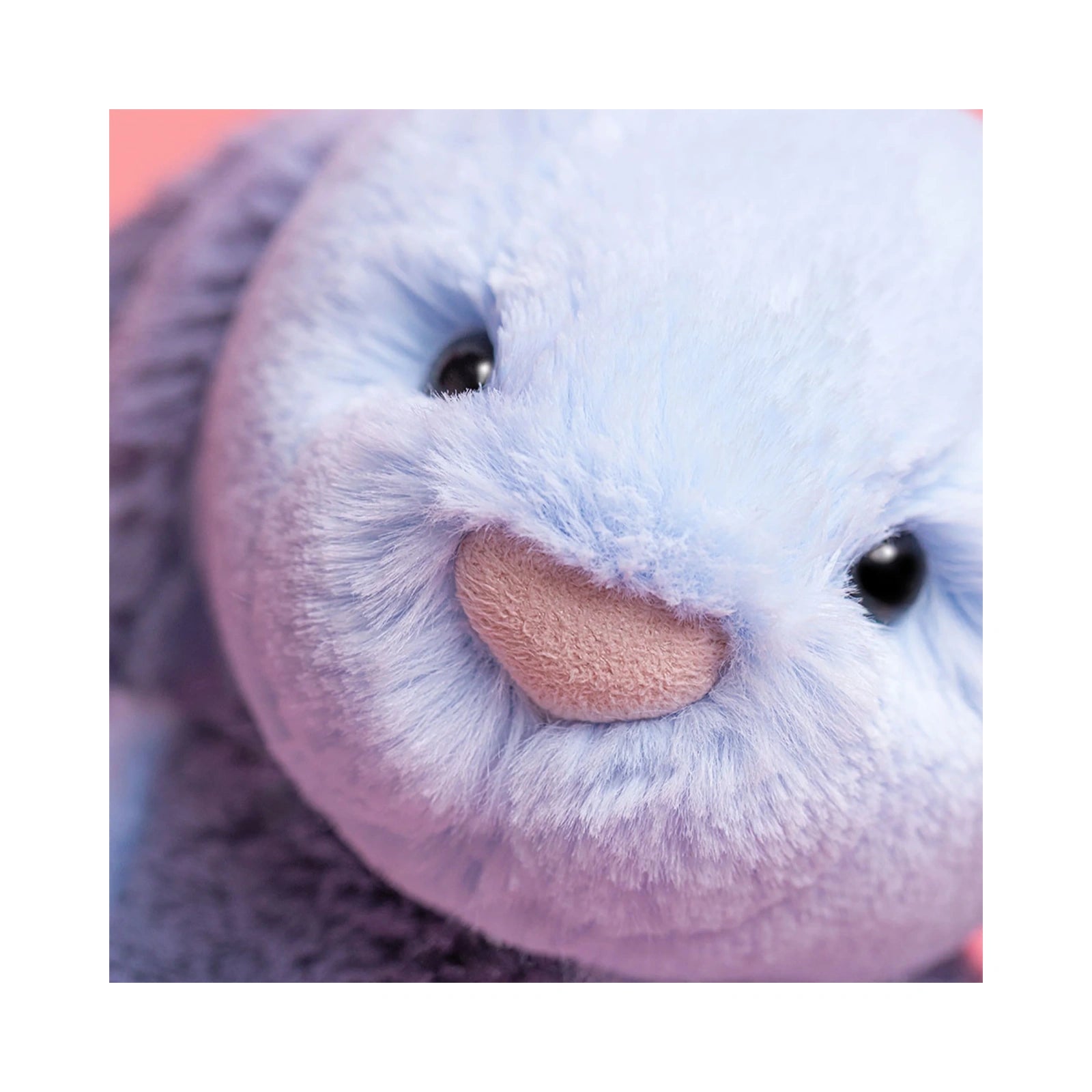 A close up detail of the Jellycat Puddlesea Bunny Original showing its soft light blue plush fur, small black eyes, and a pink textured nose.