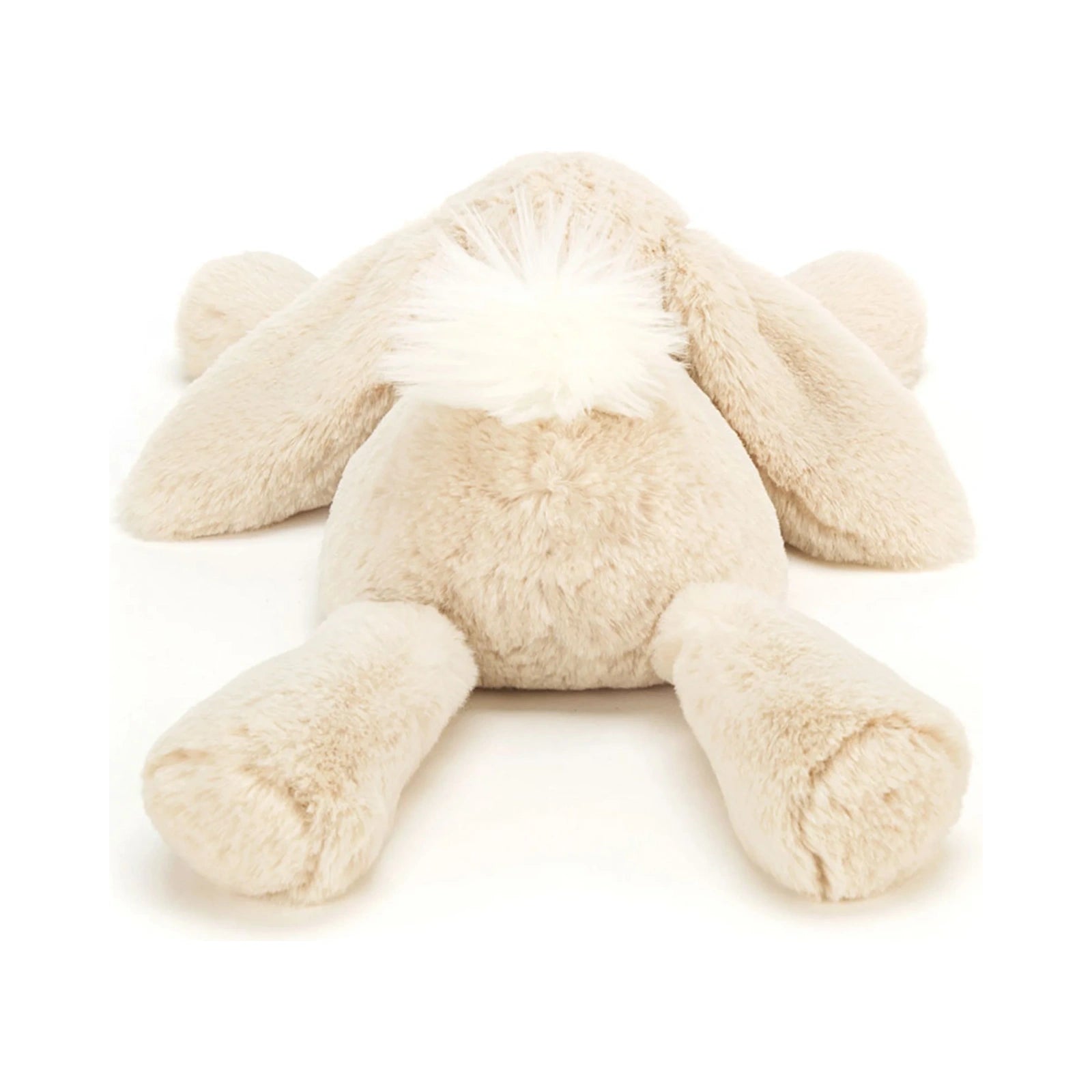The back view of a beige Jellycat Smudge Rabbit Medium plush toy lying flat, featuring long floppy ears and a fluffy white tail.