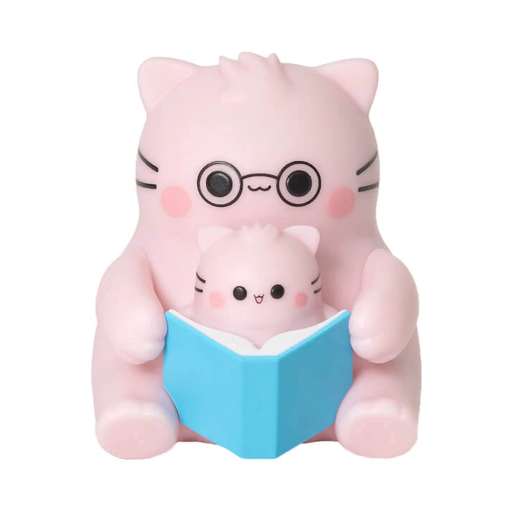 Pembe the Pink Cat mini figurine showcasing a parent pink cat wearing round black glasses reading a blue book with a baby pink cat.
