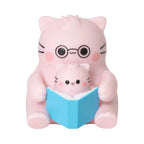 Pembe the Pink Cat mini figurine showcasing a parent pink cat wearing round black glasses reading a blue book with a baby pink cat.