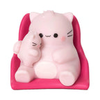 A Pembe the Pink Cat mini figurine depicting a light pink round cat holding a small kitten while sitting in a hot pink miniature chair.
