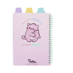 A light pink Pembe Project Book featuring a cartoon illustration of a pink cat hugging a kitten under the words Warm Hearts and Warm Hugs, with a green spiral binding and pastel purple, yellow, and blue cat head shaped tab dividers.