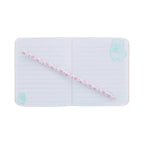 An open lined journal from the Pembe the Pink Cat stationery set featuring light green lines and cute mint cat illustrations in the corners, with a matching pink pencil decorated with small pink cat faces lying diagonally across the pages.