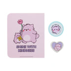 Pembe the Pink Cat stationery set featuring a lavender notebook with cute cartoon cats holding flowers under the phrase Shine with Kindness, paired with a small circular blue badge and a heart shaped cat badge.